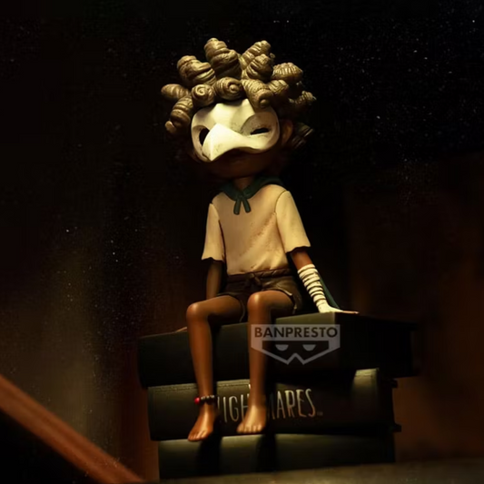 Figurine Low Monitor Top Figure Vol. 2 – Little Nightmares III, assis sur une pile de livres avec son masque d'oiseau.