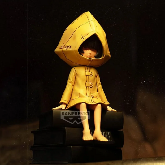 Figurine Six Monitor Top Figure Vol. 1 – Little Nightmares, assise sur une pile de livres noirs en imperméable jaune.